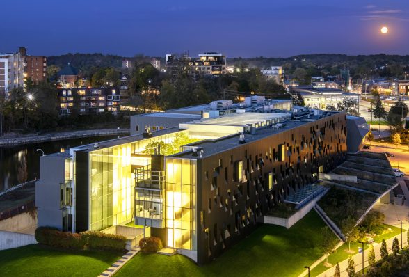 a building lit up from the inside with many large glass windows photographed at night time