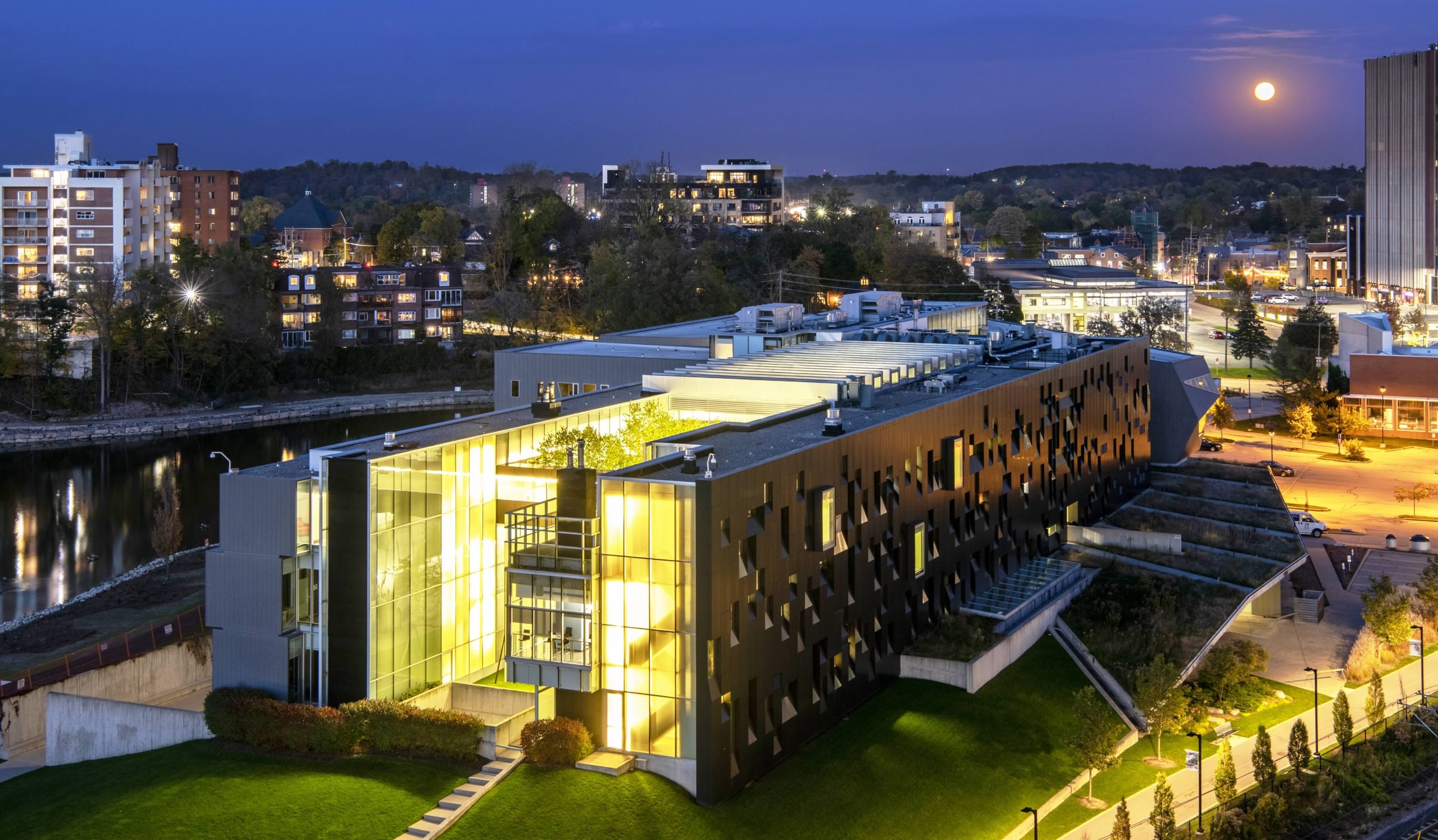 a building lit up from the inside with many large glass windows photographed at night time