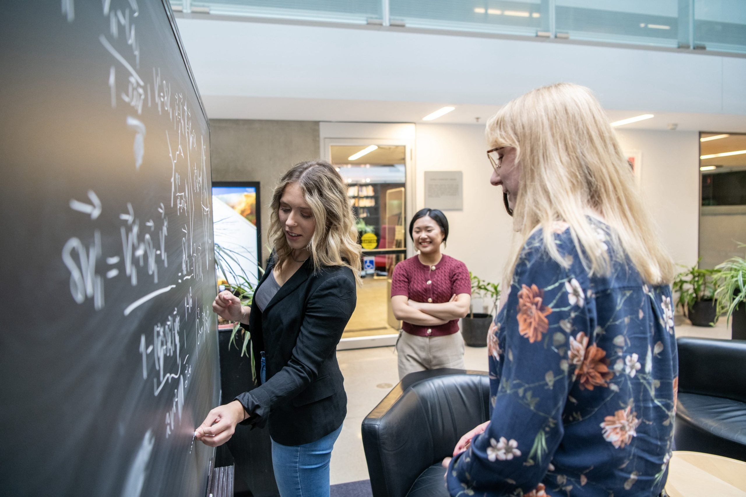 a group of three women working at the blackboard